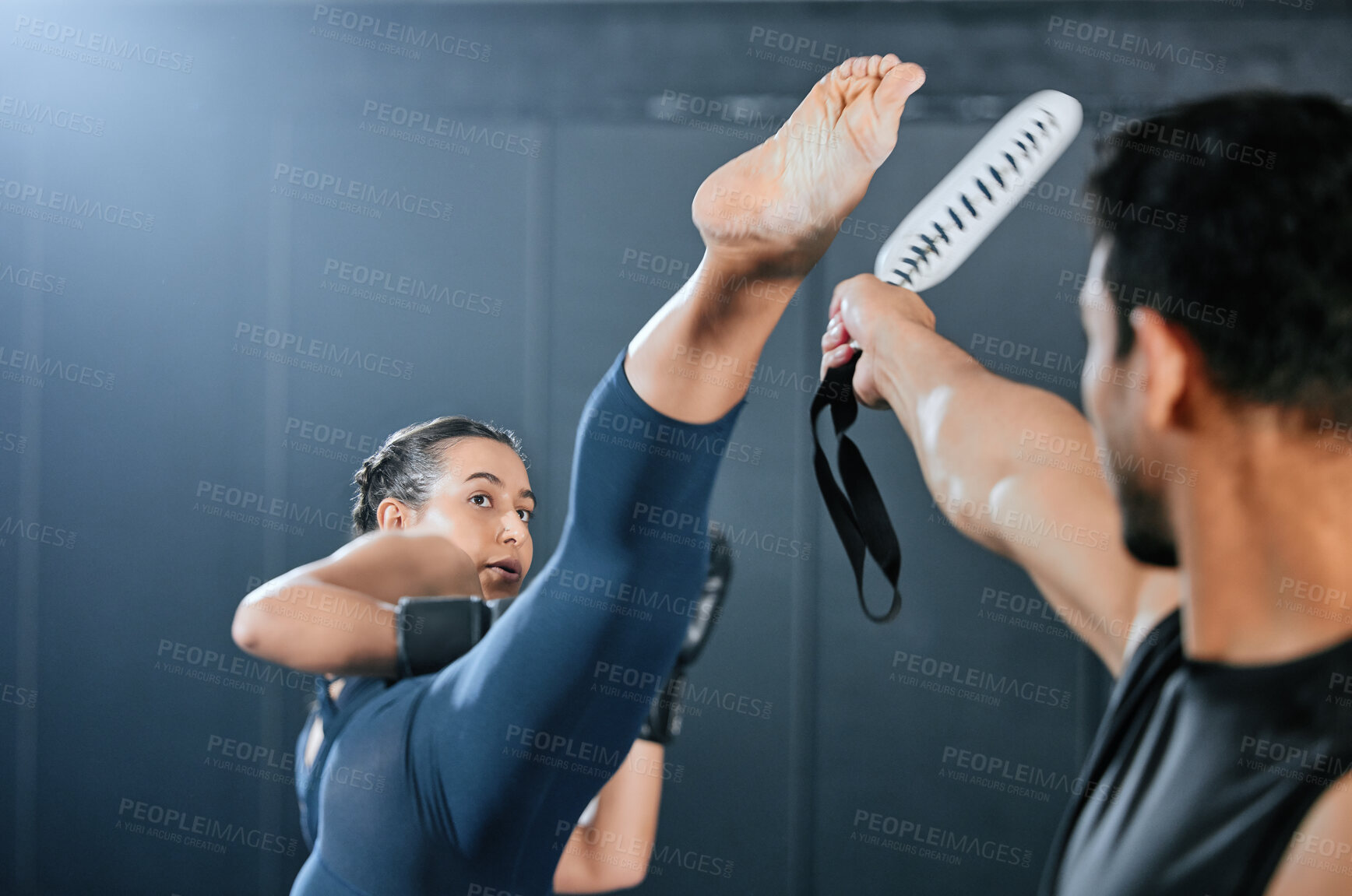 Buy stock photo Fit, active and strong woman doing exercise, workout and training while kickboxing with instructor at a gym. Confident female athlete kicking, doing cardio and a fitness session with a trainer