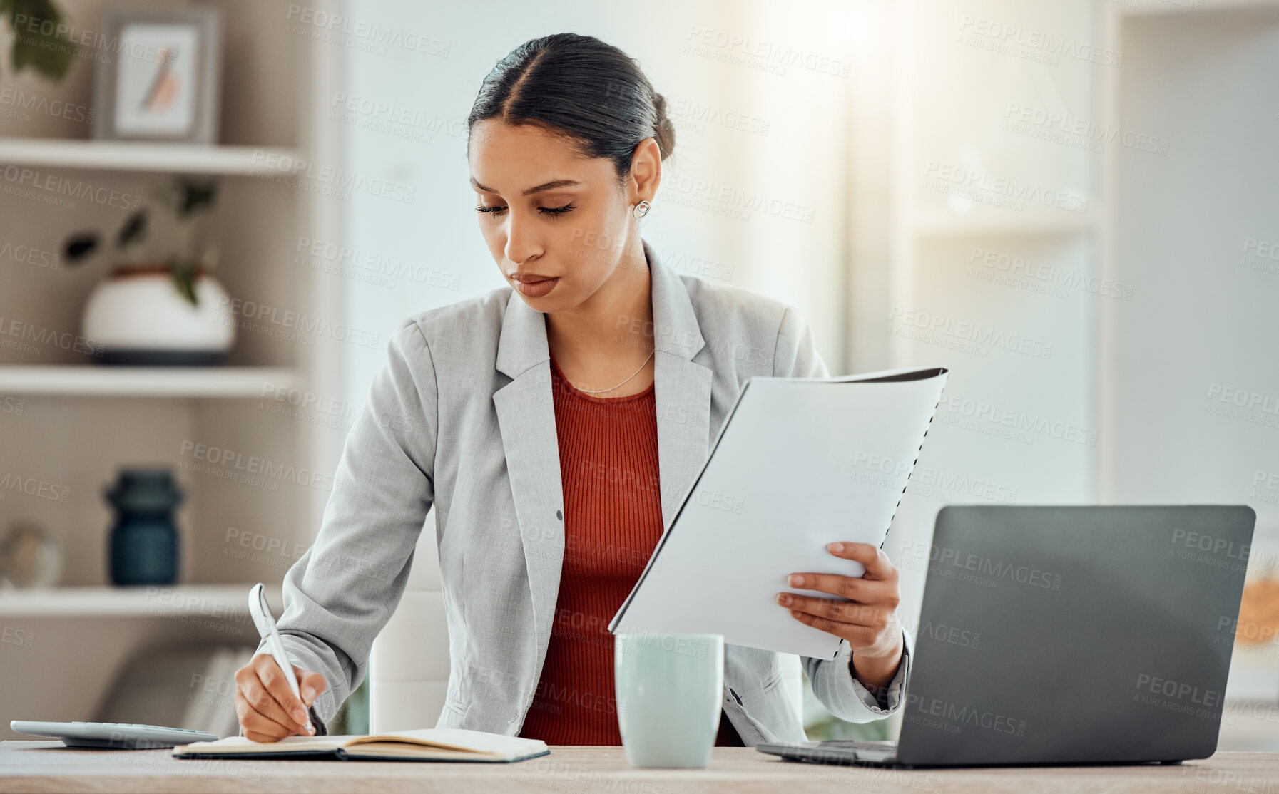 Buy stock photo African Business woman planning, taking notes and writing in a notebook while reading a report, document or paperwork in an office alone at work. One serious corporate professional working at a desk