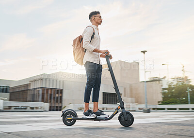 Buy stock photo Riding an electric scooter into a carbon, emission free future. A casual business man driving an escooter in a city street on the morning commute. Eco friendly travel and transport is the way forward