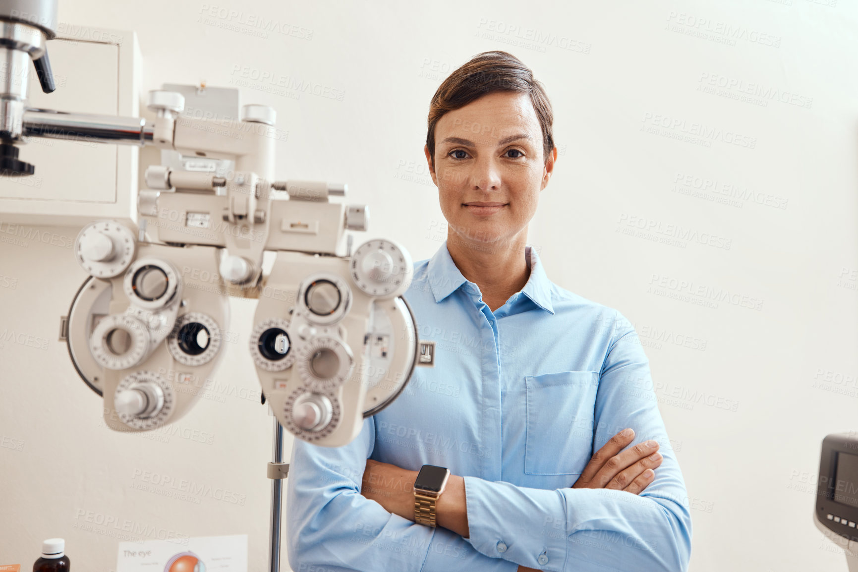 Buy stock photo Confident, happy and proud optometrist standing with arms crossed, ready for checkup and preparing equipment in an optometry office. Smiling, successful and wellness portrait of an ophthalmologist 