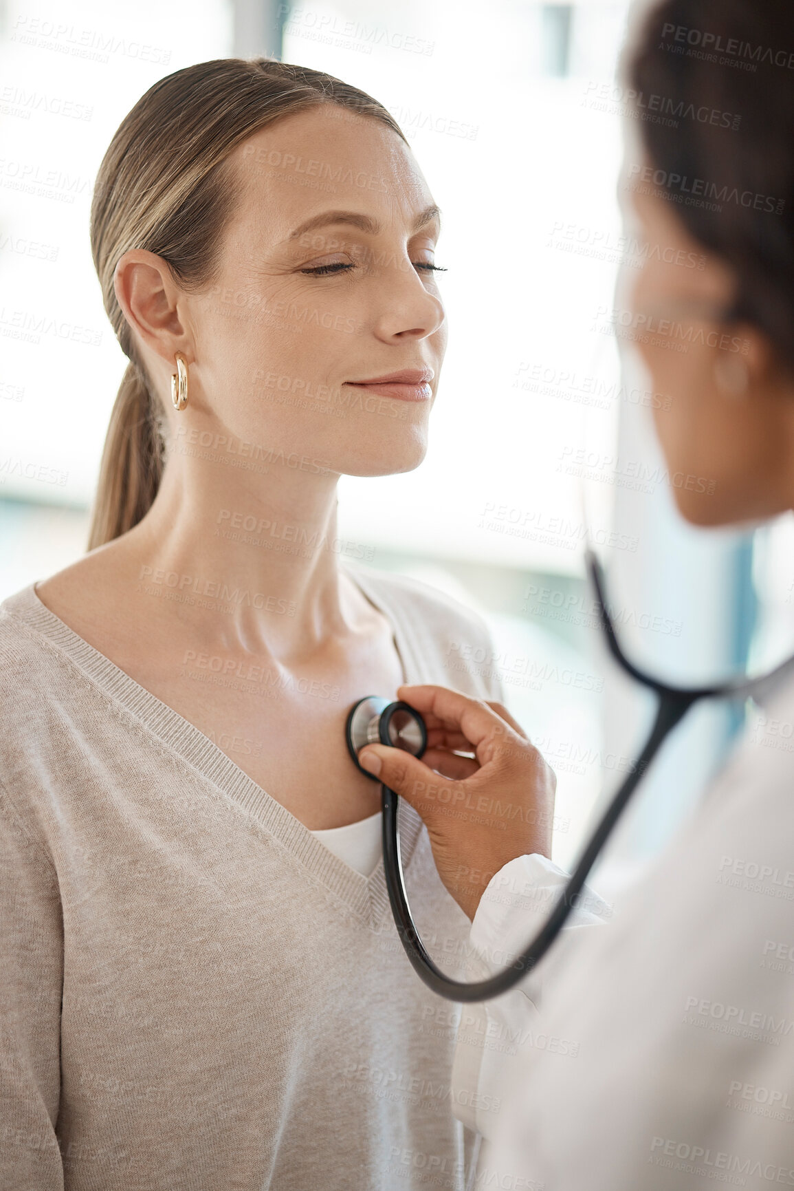 Buy stock photo Checking and hearing heart rate with a working doctor consulting the wellness and health of a woman. Clinic checkup with a medical professional and patient at a healthcare center or hospital
