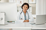 Medical doctor working on laptop and desktop computer, networking with people online and sitting at a desk at a hospital. Portrait of a black female professional healthcare worker in office at clinic