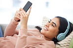 Phone, music and relaxation with a young woman lying down, resting and streaming songs online. Enjoying free time, relaxing and resting over the weekend at home. Browsing social media on the internet