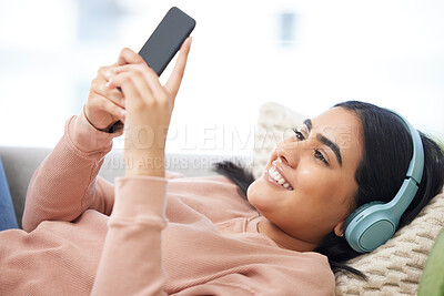 Buy stock photo Phone, music and relaxation with a young woman lying down, resting and streaming songs online. Enjoying free time, relaxing and resting over the weekend at home. Browsing social media on the internet