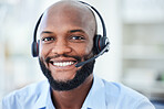 Portrait of male call center agent with a headset working in a corporate office doing crm. Cheerful, young and African ecommerce customer service representative or support hotline operator at work.