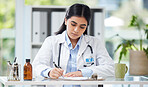 Doctor writing a prescription or recommending medication letter while sitting at her desk. Professional female GP, surgeon or physician writing a medical file and report in clinic alone in a office