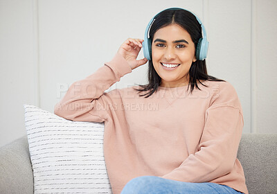 Buy stock photo Happy, relaxed and beautiful female with headphones listening to music sitting on the couch at home. Portrait of a young female streaming a podcast online and enjoying relaxing in the living room