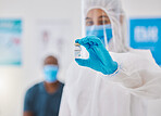 Covid vaccine, cure or treatment for covid19 held by a healthcare professional in a hospital. Portrait of a doctor wearing a protective hazmat suit holding a shot of medicine in a clinic or hospital