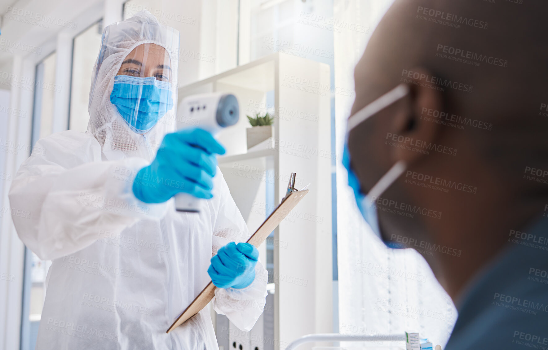 Buy stock photo Healthcare worker, checking the temperature of male covid patient for safety against virus pandemic, wearing protective suit. Medical doctor in a hazmat suit, using a thermometer to prevent outbreak