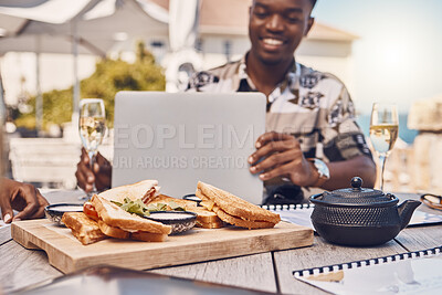 Buy stock photo Man working on laptop eating lunch at restaurant, business meeting with friends and planning collaboration with food at cafe. Happy African worker on internet with computer and team strategy in city