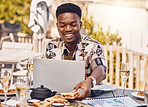 Man working on a laptop while eating lunch at an outdoor restaurant with 5g service in the city. Casual employee doing research on internet with a computer while having sandwich and champagne at cafe