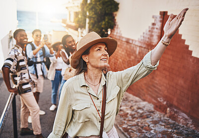 Buy stock photo Travel, education and a teacher with students on school field trip, on urban tour. Woman, city guide and group of happy tourists, pointing at local architecture and learning on international holiday.