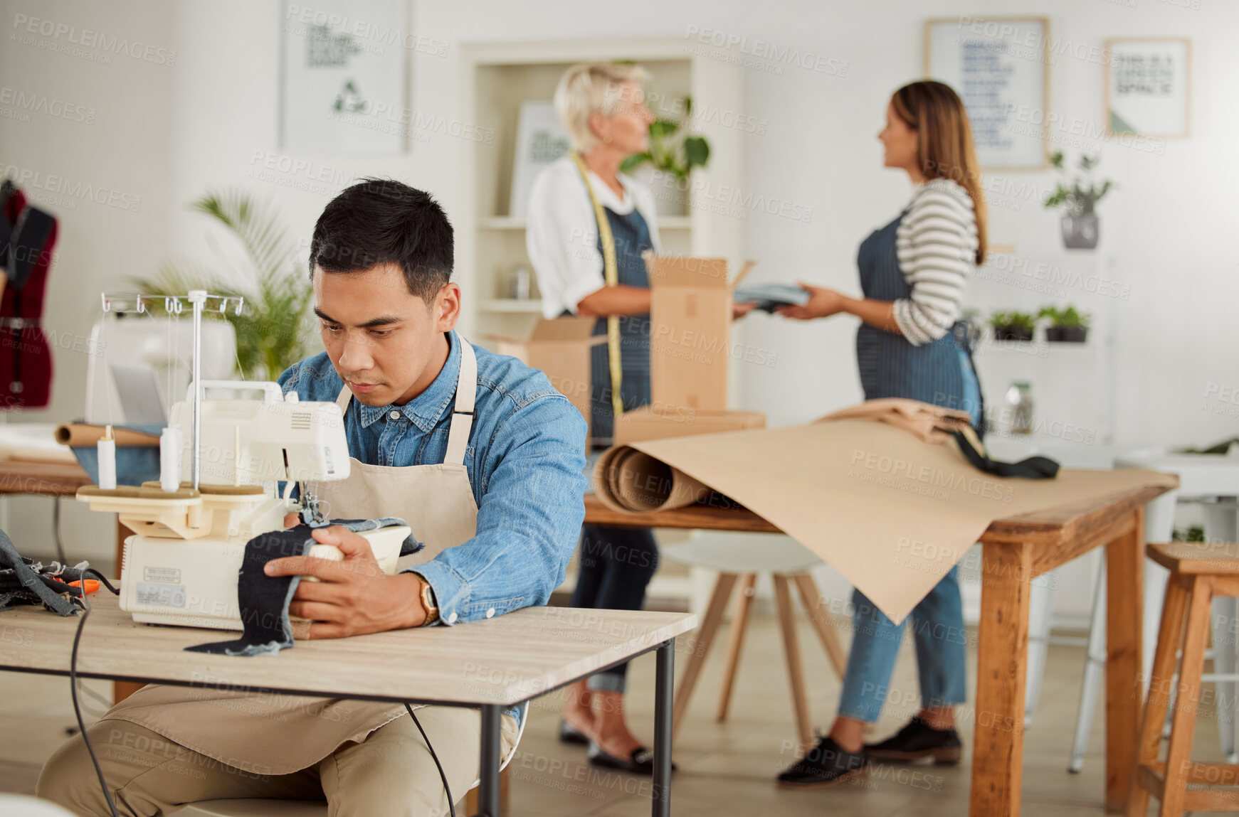 Buy stock photo Tailor, seamstress and creative designer working on a sewing machine in a design studio or workshop. Fashion, style and creativity with a young man knitting and stitching while making trendy clothing