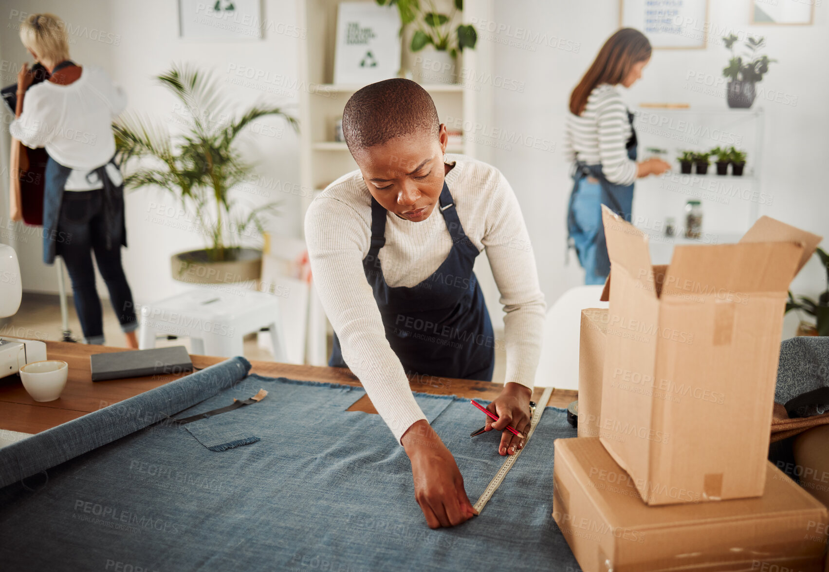 Buy stock photo Fashion designer, tailor and creative entrepreneur measuring material and textile for fashionable and trendy clothing in her startup business. Using a tape measure to trim or cut fabric for design