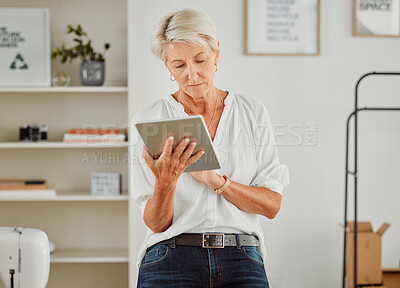 Buy stock photo Senior businesswoman, manager or designer reply, responding or sending notification of online orders from handheld tablet. Old clothing producer or business owner serious searching the web in studio.