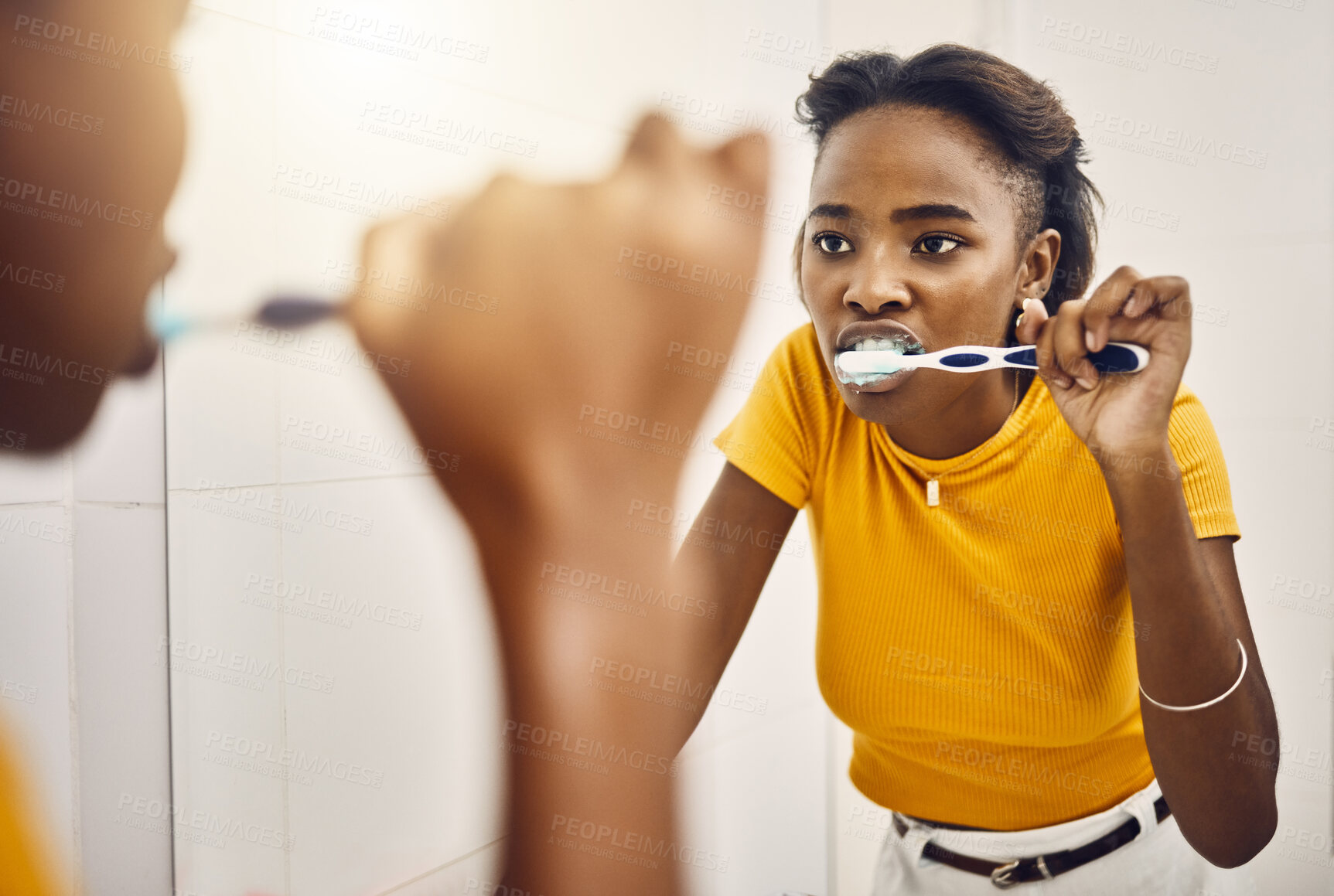 Buy stock photo Brushing teeth, dental hygiene and oral care with a young woman looking at her reflection in the bathroom mirror at home. Maintaining mouth, teeth and gum health with a daily toothcare routine