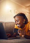 Online shopping young, happy and smiling African lady with bank, credit or gift card. Excited, comfortable and cheerful female typing on laptop searching, browsing and buying present from home.