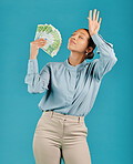 Woman showing off money, looking rich with cash prize and winning the lottery while standing against a blue studio background. Female billionaire holding bank notes and looking confident with salary