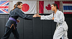Women, martial arts and fighting at a dojo. Taekwondo, karate and sports training adults sparring at the gym for a fight. Athlete, aikido and practicing females at an international competition.