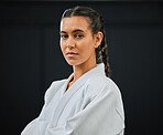 Karate, judo or taekwondo woman in white kimono for martial arts, jiu jitsu and kung fu against a black studio background. Portrait of a determined, serious and focused fighter ready for combat