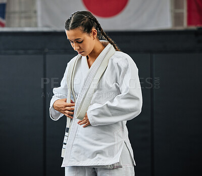 Buy stock photo Mma, karate and self defense with a young woman getting ready in her gi or uniform for training, exercise and practice. Workout, sport and fighting with a female athlete standing in a gym or studio