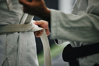 Buy stock photo Karate learning, training and workout of a sport student and coach getting ready for a fight class. Defense expert hands tie a belt in a dojo, workout studio or wellness club about to work on fitness