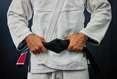 Buy stock photo Professional karate master holding a black belt against a dark background in a dojo. Trainer, coach or leader prepared and motivated for training, fitness exercise and fight practice in a dojo