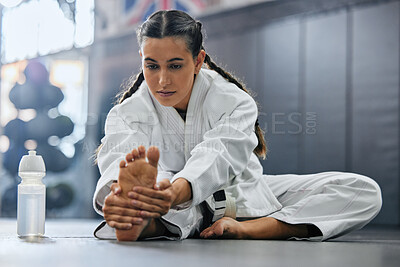 Buy stock photo Female karate school student doing a warmup, stretch or exercise with serious, determine and focus before workout. Sports woman or coach leg stretching at a dojo studio, gym or martial arts club