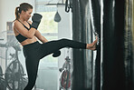 Kickboxing, fitness and boxing exercise of a sport woman athlete training with a punching bag. Motivation, focus and workout mindset of a strong female in a boxing gym, sports studio or wellness club