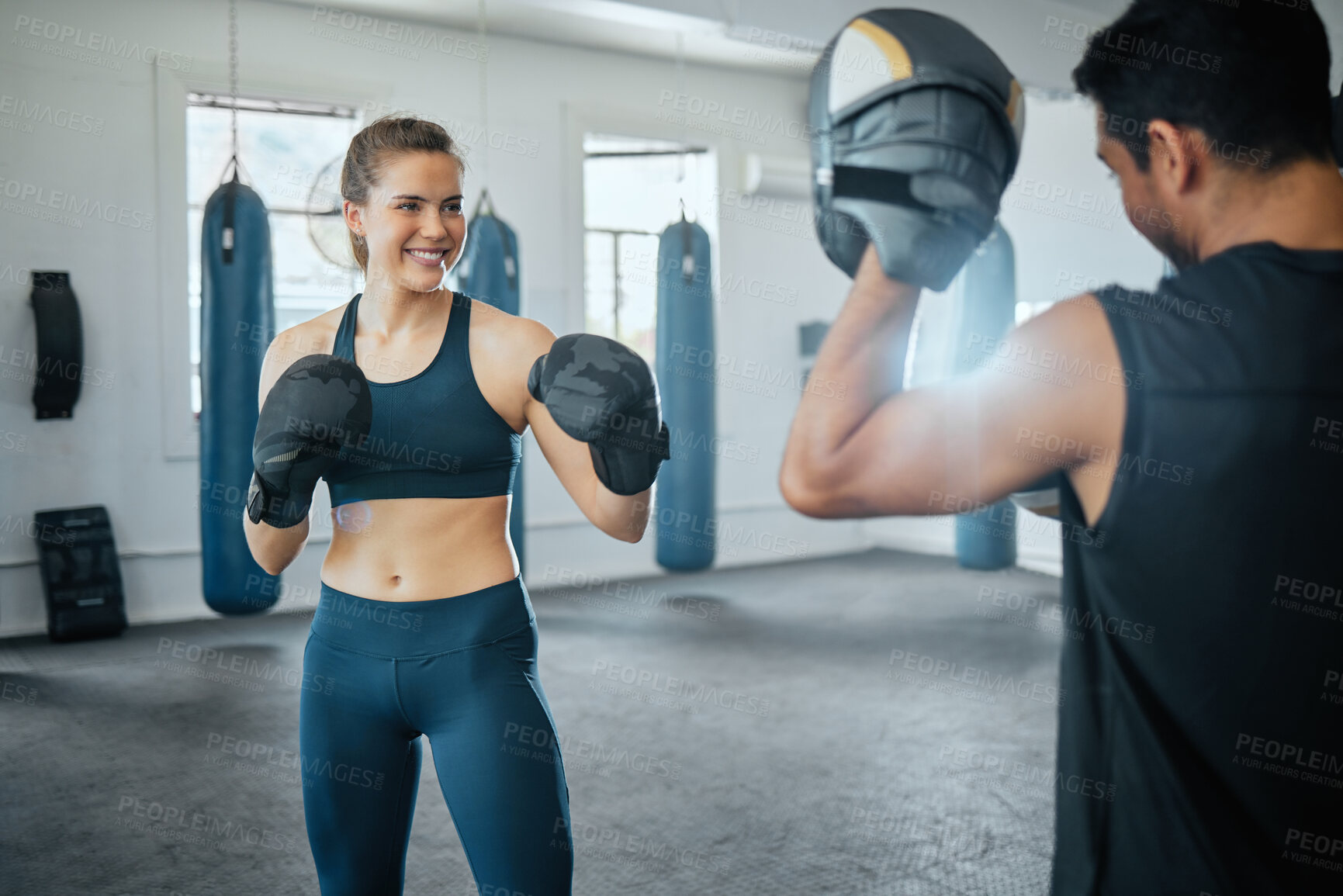 Buy stock photo Boxing gym, combat sport and woman training for fight, exercise and workout in fitness club. Happy female, strong athlete and smile sports people fighting with personal trainer, coach and kick boxer