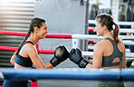 Healthy, athletic and sporty young women sparring with boxing gloves indoors. Beautiful girls keep active with friendly competition through fitness and exercise.  Happy fist bump in the sports center.