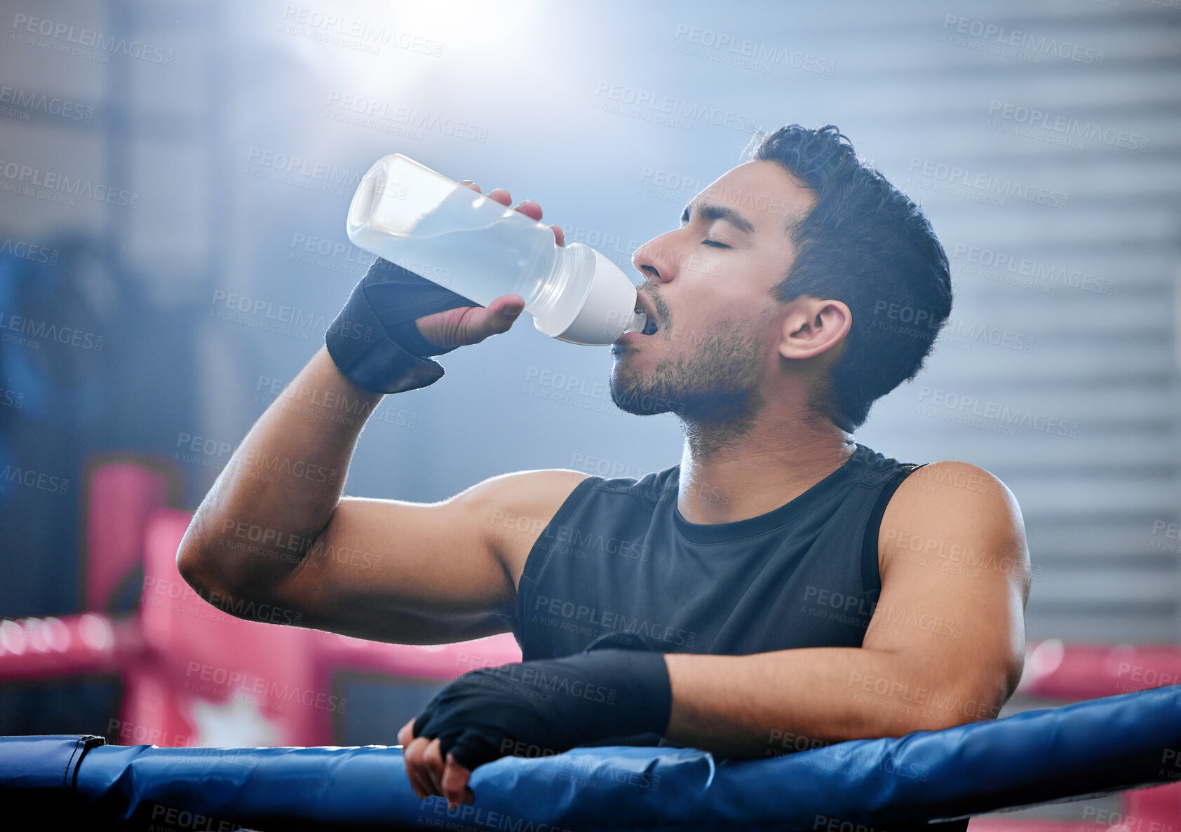 Buy stock photo Fit, active and healthy boxer drinking water, on break and staying hydrated in routine workout, training or boxing ring exercise. Sporty, athletic or strong man after kickboxing fight or sports match