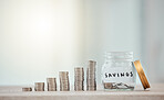 Finance, budget and saving money or coins by depositing currency, cash and pennies in a glass jar on copy space background. Closeup of piled, stacked and heaped cents for planning or future investing