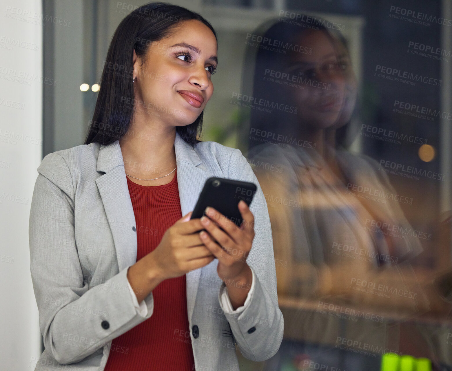 Buy stock photo Thinking, phone and smiling woman texting, browsing the internet or using a mobile app with good network while working late at night. Hardworking entrepreneur checking investment growth online