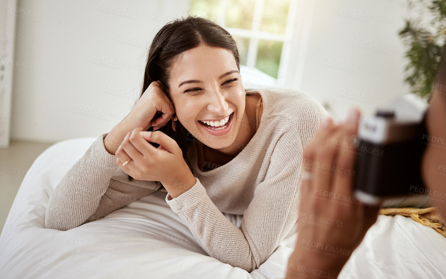 Buy stock photo Beautiful, attractive and happy woman having a home photoshoot while lying in bed and smiling. Young excited female having pictures or photos taken while relaxing in her bedroom