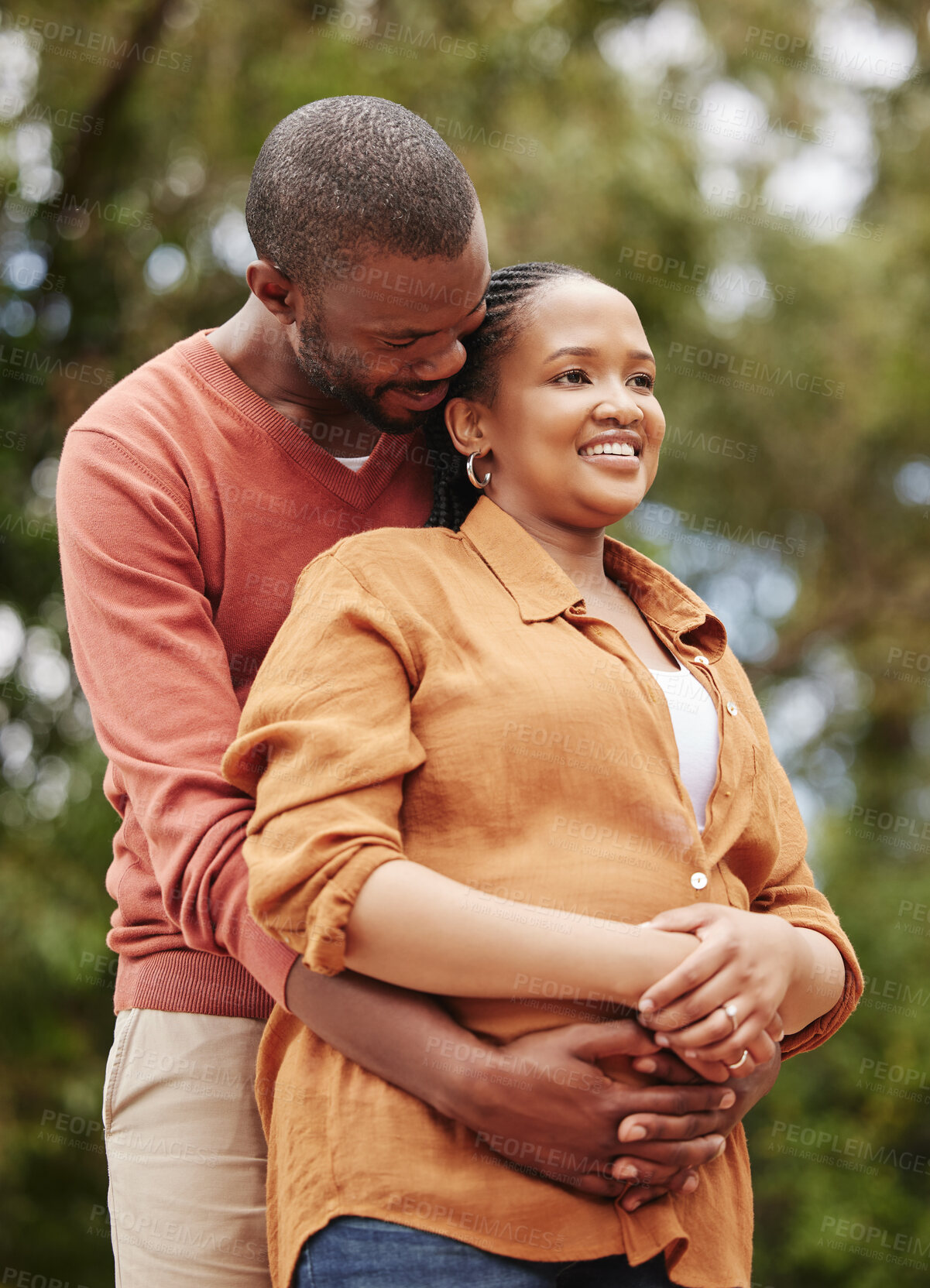 Buy stock photo Romantic, loving and caring husband hugging his wife from the back in nature while on a date. Young, African and happy couple embracing each other while spending quality time together outdoors.