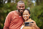 Trendy, modern couple taking selfie on phone while on a romantic date in a park and sharing relationship status on social media app. Smiling, in love married husband and wife capturing happy memories