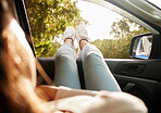 Relaxed, content and happy woman relax while enjoying the sunny morning in a car. Back view of female with feet out her window taking a break from driving sitting and loving the summer sunshine day