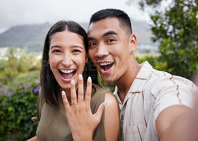 Buy stock photo Engagement, ring and celebration with a young couple announcing their happy news and special occasion. Closeup portrait of a man and woman taking a selfie after getting engaged to be married outside 