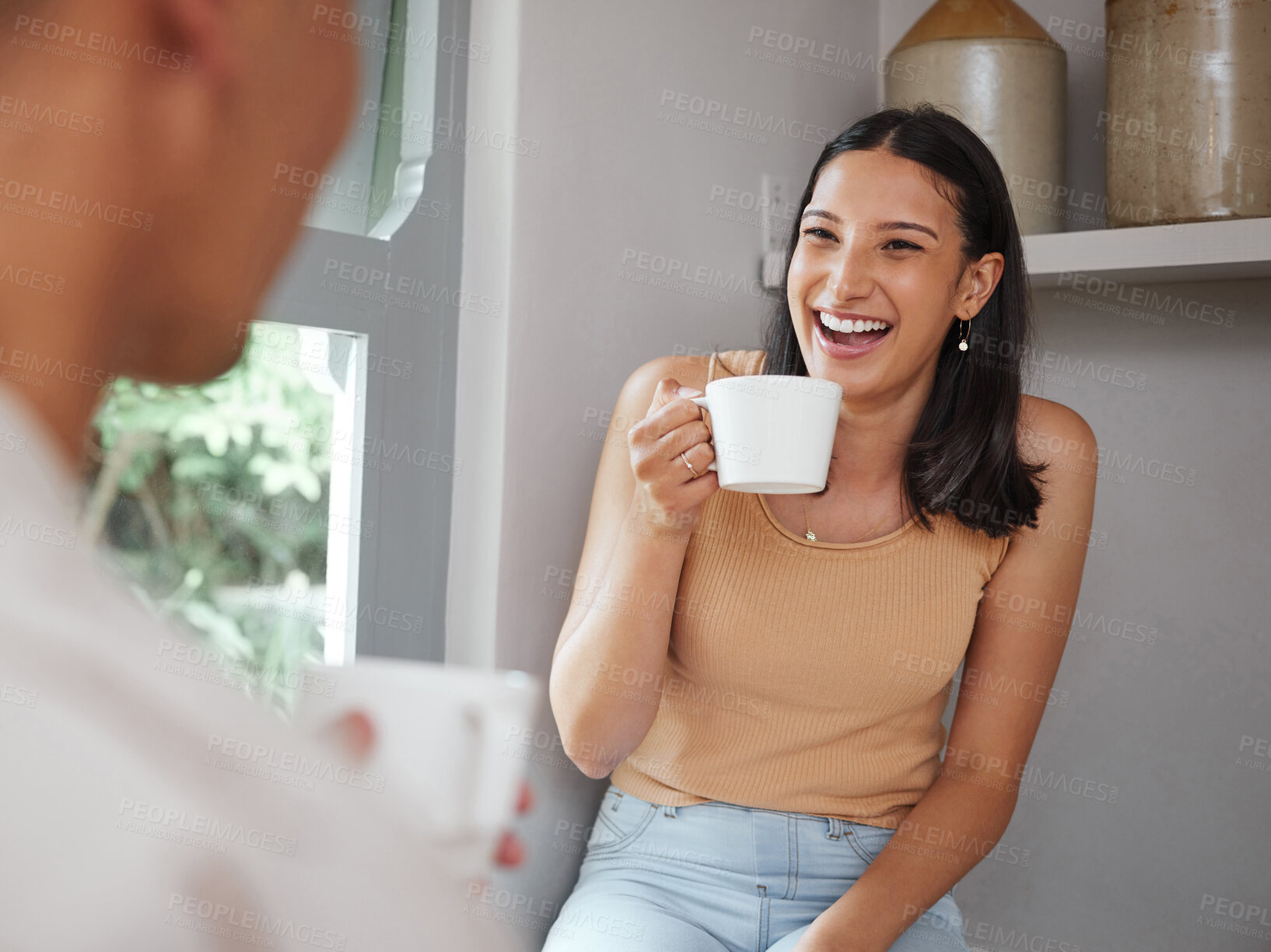 Buy stock photo Happy, carefree and laughing woman drinking coffee in the morning and having fun with her boyfriend at home. Young and excited female laughs at a funny joke while and enjoying time with her partner 