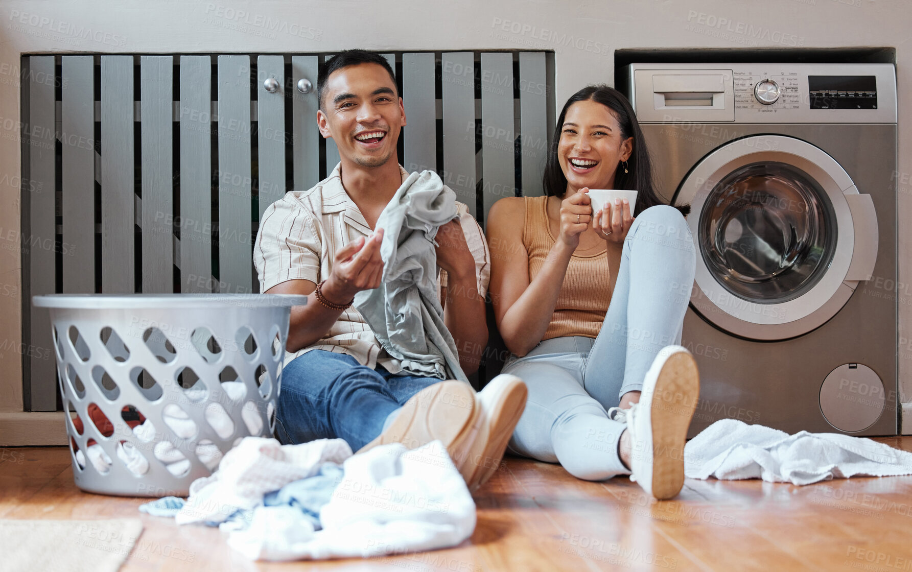 Buy stock photo Happy, relaxed and responsible couple doing laundry, household chores or cleaning together on the weekend at home. Young millennial boyfriend and girlfriend enjoying their new modern washing machine