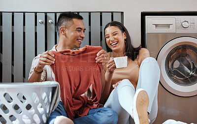 Buy stock photo Carefree and funny couple doing laundry and relaxing together at home in the morning. Silly, goofy and playful lovers laughing and giggling while cleaning the washing, and doing house chores