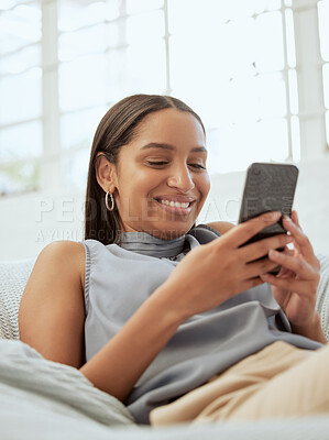 Buy stock photo Happy, relaxed and modern woman with a phone texting, checking social media app or reading message online while relaxing on sofa indoors at home. Casual female browsing the internet for funny content