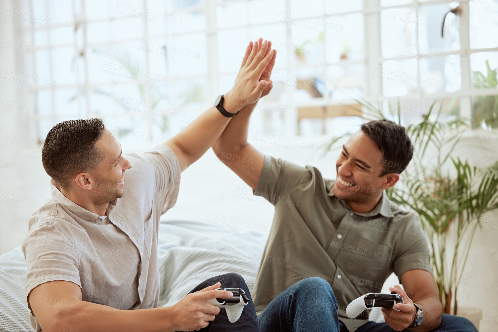 Buy stock photo Men high five, celebrate and enjoy playing video games in the sofa at home. Happy, cheerful and best friends having fun and winning while holding wireless controllers with live online game