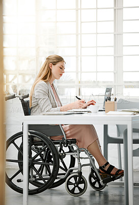 Buy stock photo Professional, disabled business woman in wheelchair reading documents, writing or making notes on office desk sitting by laptop. Female entrepreneur with disability doing contract paperwork with pen.