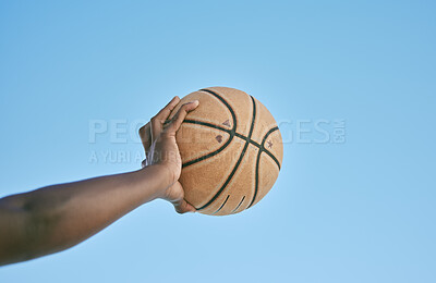 Basketball, active and sports man hand holding ball showing victory, power or athletic fitness from below with blue sky background. Player, black man or athlete arm practicing for professional league