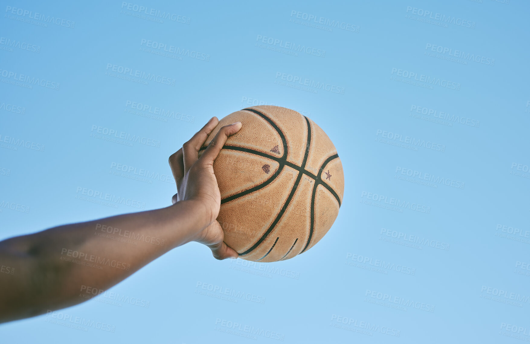 Buy stock photo Basketball, active and sports man hand holding ball showing victory, power or athletic fitness from below with blue sky background. Player, black man or athlete arm practicing for professional league