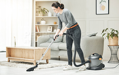 Buy stock photo Vacuuming, cleaning and housework done by a mother, house wife or girlfriend using a vacuum cleaner. Stay at home mom, maid or housekeeper doing household chores and tidying in a modern living room