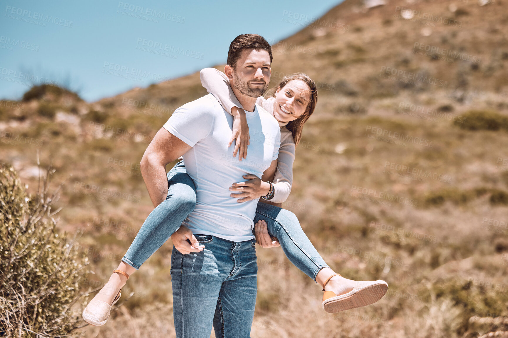 Buy stock photo Happy and in love couple having fun in nature and enjoying quality time together. Cute and relax boyfriend piggyback or carrying girlfriend with a smile on a bonding and romantic countryside date 