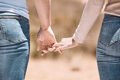 Buy stock photo Affectionate couple holding hands showing love, caring and bonding outside together in nature. Loving boyfriend and girlfriend expressing unity, understanding and trust in their relationship 
